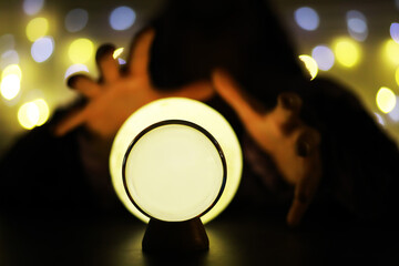 Crystal Ball on the table with bokeh, lights behind. Glass ball with colorful bokeh light, prediction concept.
