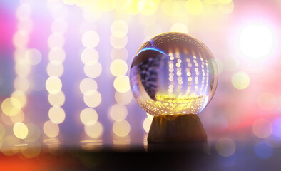 Fototapeta na wymiar Crystal Ball on the floor with bokeh, lights behind. Glass ball with colorful bokeh light, celebration concept.