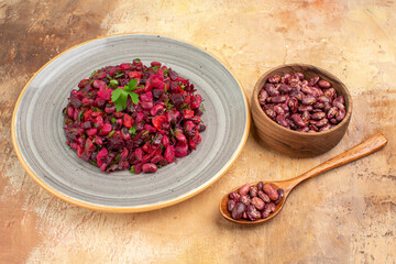 Side view of delicious salad with beetroot and bean and beans inside and outside of pot on mixed color table
