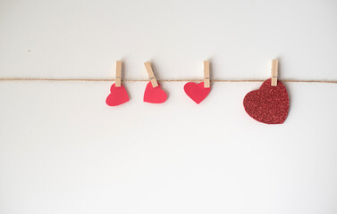 Many red hearts on rope with wooden clothespin on white background. Lovely valentine day, 14th February. Feeling in love. Happy wedding and blissful life. Feel catch and grab by love