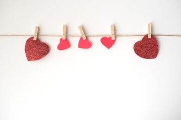 Many red hearts on rope with wooden clothespin on white background. Lovely valentine day, 14th February. Feeling in love. Happy wedding and blissful life. Feel catch and grab by love