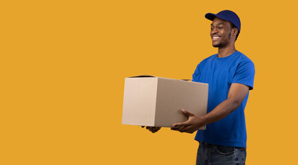 Black delivery guy holding cardboard box giving it to side