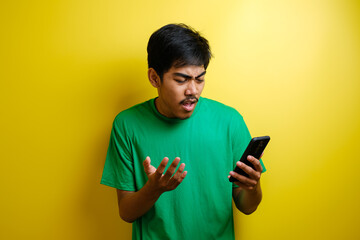 Attractive young asian man reading texting chatting on his phone, bad news, sad crying expression