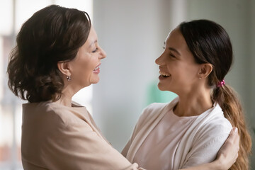 Close up overjoyed middle aged mother and grownup daughter hugging, expressing gratitude and care, excited by good news, happy young woman with mature mum cuddling, enjoying leisure time together