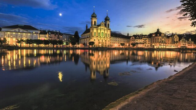 TIME-LAPSE: colorful sunset of Lucerne city on Lake Lucerne in Central Switzerland. Jesuitenkirche or Jesuit Church of St. Francis Xavier reflects on Reuss river. Famous landmark of historical city