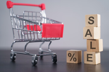 Text "SALE" on wooden cube with shopping cart.