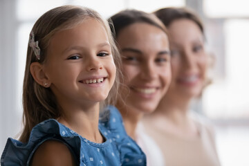 Head shot portrait focus on smiling little girl looking at camera, aging process concept, three...