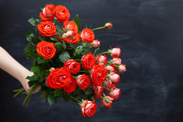 Fototapeta na wymiar bouquet of roses in hand on a chalkboard background