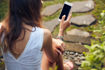 Caucasian young woman using modern smartphone in oriental garden.