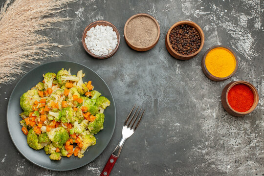 Top view of set of different spices in brown bowls and vegetable salad with fresh broccoli stock image