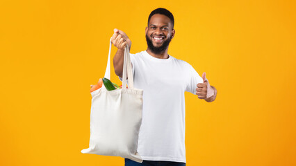 African Man Holding Eco Bag Gesturing Like, Yellow Background