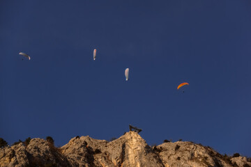 Fototapeta na wymiar four paraglider on blue sky and high rocky mountain with skywalk