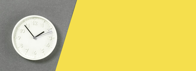 Plain wall clock in the center of grey and yellow background. Ten o'clock. Close up web banner with...