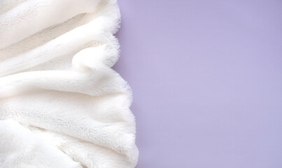 Fototapeta na wymiar White delicate soft background of plush fabric folds on light violet background. Copy space. Flat lay. Details of warm winter clothes