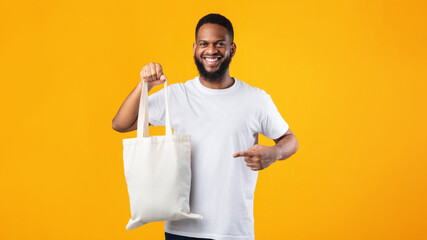 Smiling Black Guy Holding Eco Bag Standing Over Yellow Background