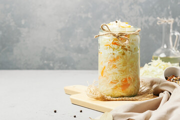 Sauerkraut in a glass jar with ingredients on a concrete background with copy space.