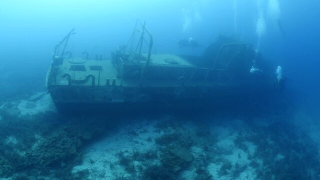 scuba divers exploring shipwreck scenery underwater ship wreck deep blue water ocean scenery of metal underwater