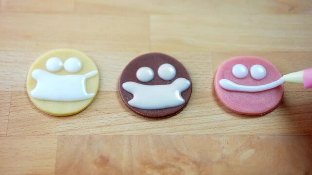 Christmas diverse cookies on a wooden table. Decorating black and white cookies as emoji with a surgical face mask made of frosting icing. Social distancing and holidays.