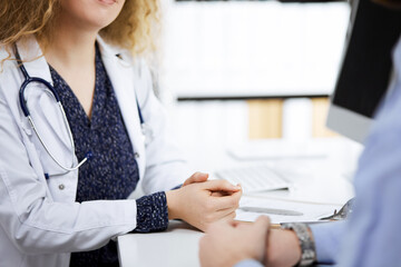 Female doctor and male patient discussing current health examination while sitting in clinic,...