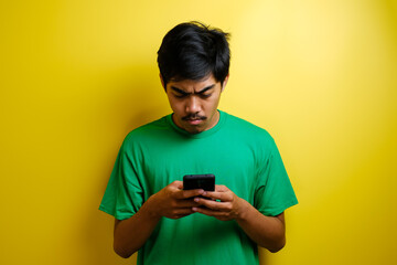 Angry Asian man plays mobile game on his smartphone.