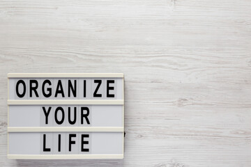 'Organize your life' on a lightbox on a white wooden background, top view. Flat lay, overhead, from above. Space for text.