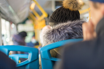 Back view of hiker traveler, woman in woolen hat sitting inside the bus in winter season.