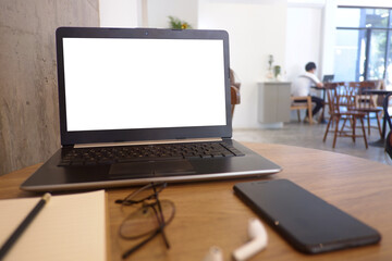 Front view of wooden office desk with the labtop, keyboard, smart phone and the other office supplies at the modern space