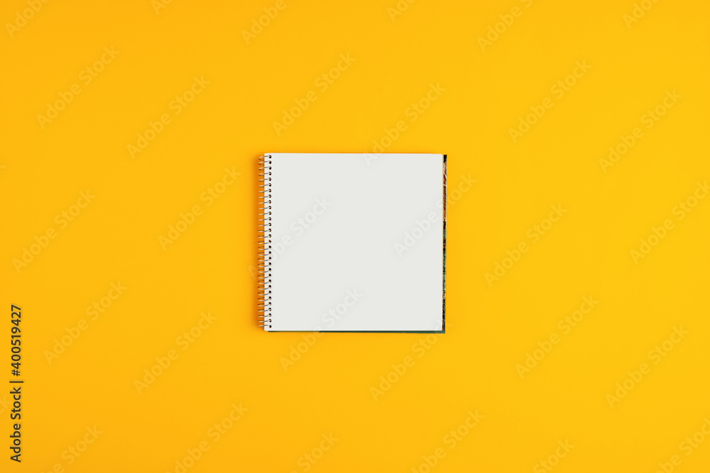 Poster blank spiral notepad or notebook in square shape on yellow background