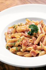penne amatriciana tomato and ham sauce pasta on wood table