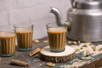 Indian chai in glass cups with metal kettle and other masalas to make the tea. 