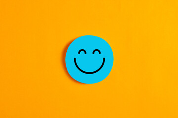 Blue round circle with a happy or smiley face icon on it against yellow background.