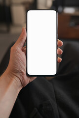 Man hold smartphone with white screen in his hand sitting on a couch in home environment