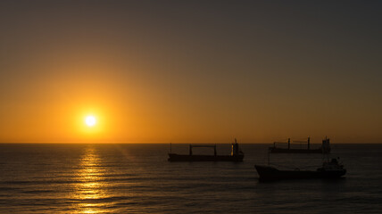 Naklejka na ściany i meble Sonnenaufgang auf dem karibischen Meer mit Transportschiffen.