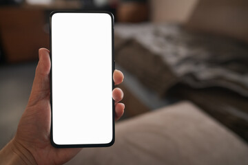 Man hold smartphone with white screen in his hand sitting on a couch in home environment
