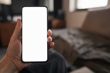 Man hold smartphone with white screen in his hand sitting on a couch in home environment