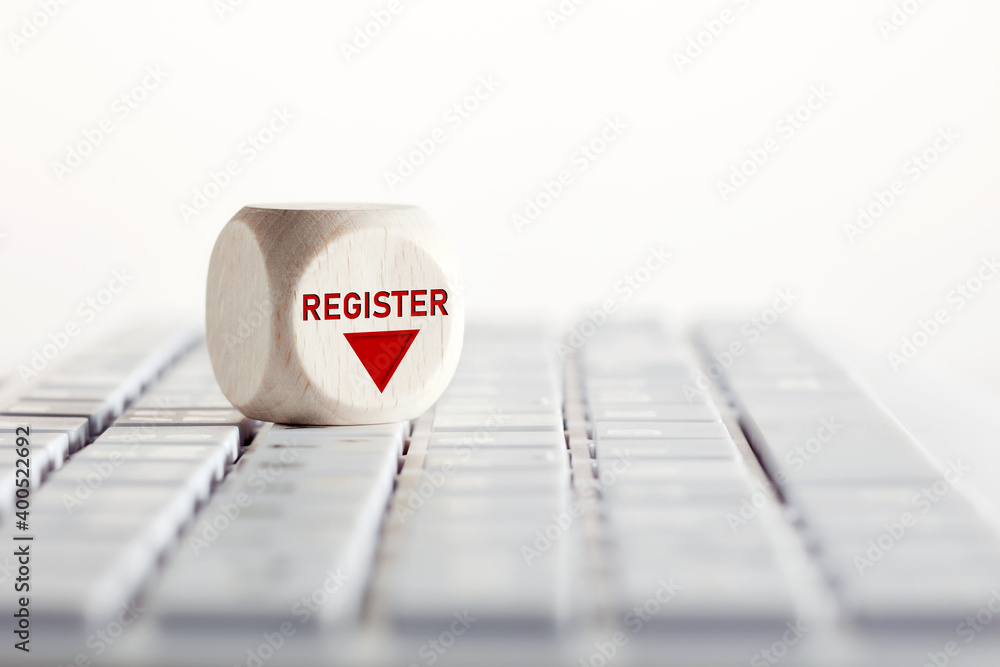 Poster the word register with arrow icon on wooden cube on computer keyboard. online registration concept.