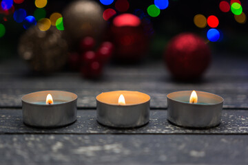 Lighted candles on a wooden base and scattered holiday decorations.