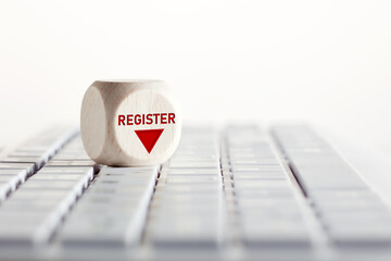 The word register with arrow icon on wooden cube on computer keyboard. Online registration concept.