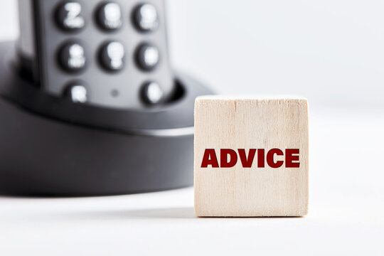 The Word Advice On Wooden Block With Telephone Background. Business Concept For Financial Services, Assistance Or Legal Consultancy.