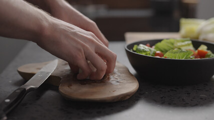 man hands take sliced mozzarella from wood board on home kitchen