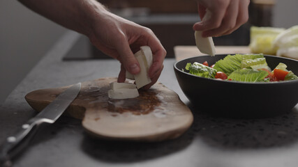 man hands take sliced mozzarella from wood board on home kitchen