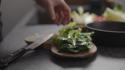 man hand take chopped romaine lettuce from wood board to make salad