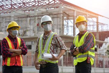 Construction engineers supervising progress of construction project stand on new factory,Engineering Consulting People on construction site holding blueprint in his hand.