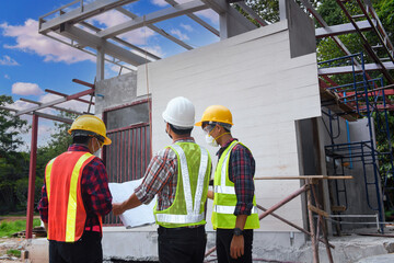 Construction engineers supervising progress of construction project stand on new factory,Engineering Consulting People on construction site holding blueprint in his hand.