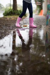 Young girl child holding umbrella at walking along the street during rain