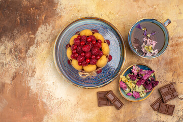 Horizontal view of a cup of hot herbal tea soft cake with fruits and flowers chocolate bars