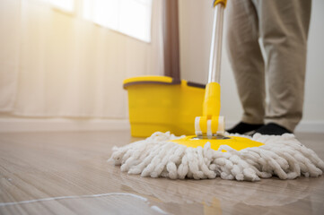 Cleaning workers mopping the wet area. There was spill water on the wooden floor in the living room.