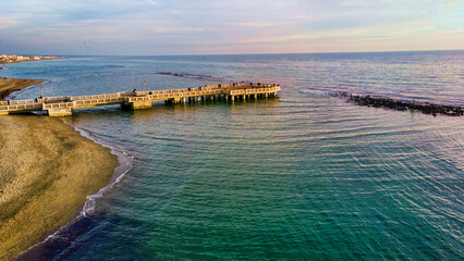 Sunset Rome aerial view in Ostia Lido beach over blue sea and brown sand, beautiful coast line with glimpse of pedestrian pier a landmark of tourist and city life © Equatore