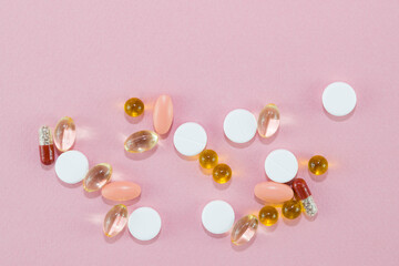 Various antibiotic tablets, vitamin D capsules, vitamin C for the treatment of coronavirus, covid-19, and other diseases on a pink background, copy space, flat bed, close-up, theme of treatment of dis
