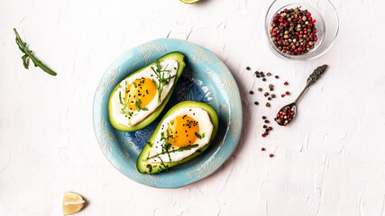 Avocado baked with eggs, fresh arugula, ground pepper on light background, top view
